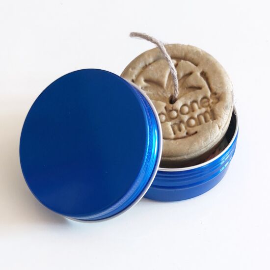 Lata de aluminio azul abierta con un champú sólido de Jabones Mami dentro